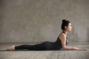 Young woman lying on the floor in baby Cobra pose.